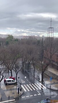 lluvia y nubes en calle de ciudad con iglesia