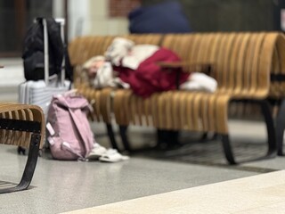 Lying Passenger With Scattered Luggage Nearby, Quiet Station Scene With Traveler Resting And Waiting Mood, Sleepy Individual Seated On Platform Bench Amidst Belongings Under Dim Lighting © vipvn