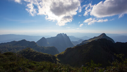Panoramic view of lush mountainous landscape with rugged peaks and serene valleys under a blue sky with white clouds, captured from a high vantage point near reference 41