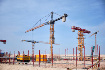 Active construction site featuring multiple tower cranes, steel scaffoldings and concrete formwork Large-scale urban development, infrastructure growth, industrial building processes