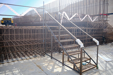 Temporary metal staircase installed at active construction site, providing safe access over steel reinforcement and concrete formwork. Construction infrastructure, site safety measures