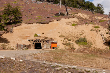 Entrance of an old coal mine surrounded with flowers and arid landscape
