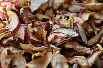 An appetizing pile of sliced dried apples with red skin demonstrates the natural texture and golden hues of dried fruits.