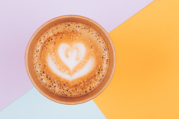 Paper cup of coffee to go on colorful trendy pastel background from above, flat lay