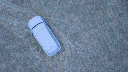 Aerial View of a Frost-Covered Car on Frozen Grass During an Icy Winter Morning.