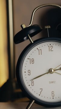 Close up vertical shot of a classic alarm clock showing time. Minimal composition with warm lighting emphasizes the concept of time management, deadlines, morning routine.