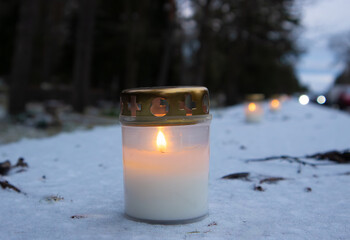 Selective focus on a row of lit memorial candles outside a cemetery, burning in memory of the dead.