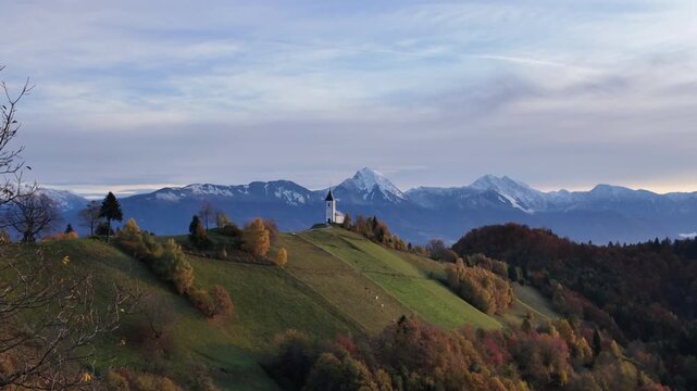 Scenic view of Jamnik church at sunrise with snow capped Julian Alps in the background, Slovenia