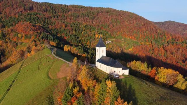 The Church of Saint Primus and Felician surrounded by colorful autumn forest in the Slovenian alps