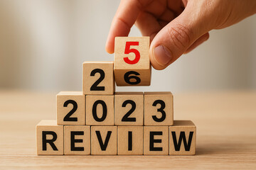 Hand Placing Red Block on Pyramid of REVIEW and 2023 – Visual Metaphor for Annual Reflection and Strategic Summary