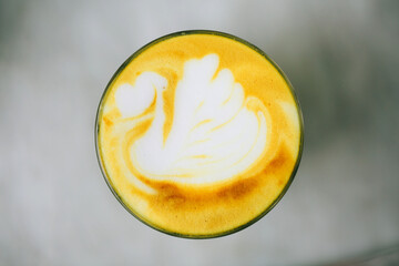 Turmeric yellow latte with swan latte art on it. Flat lay style.