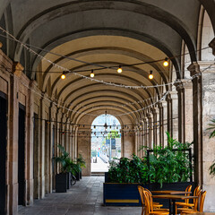 Arcade passage under the classical-style buildings with thick columns in Barcelona's Gothic Quarter.