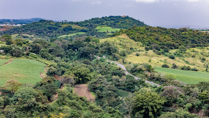 Aerial View of Winding Asphalt Road Through Lush Tropical Mountains and Coffee Plantations