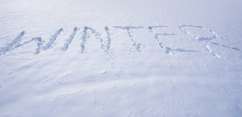 Snowy banner design in cold weather. Frosty winter text outdoors. Winter text with snowflakes. Snow background with winter text.