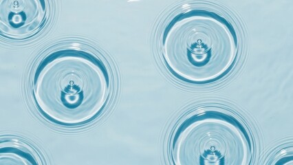 Water droplets creating ripples on calm blue surface