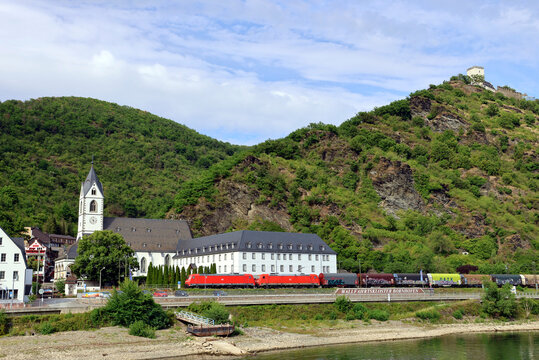 Blick vom Rhein im Oberen Mittelrheintal auf einen Zug und das Wallfahrtskloster Kamp-Bornhofen. Aussicht von einem Ausflugschiff zur Loreley.