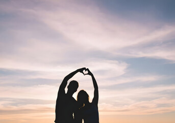 Silhouette of Romantic Couple Forming Heart Shape Against Sunset Sky, Love Concept.