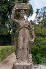 Italy - Caprarola - Palazzo Farnese - Marble statue of a caryatid in the formal gardens with lush greenery