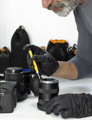 
A technician meticulously repairs a camera lens using a precision screwdriver. High-quality stock image highlighting technical skill, professional equipment maintenance, and optical service.