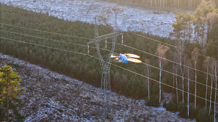 Drone flight over a high-voltage electricity pylon at sunset during winter.