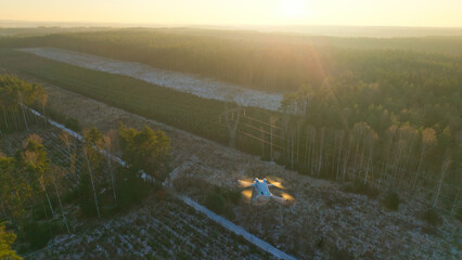 Drone flight over a high-voltage electricity pylon at sunset during winter.