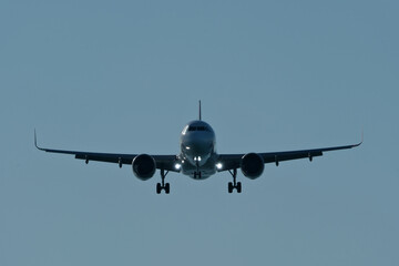 Silhouette of Commercial Airplane Approaching Runway for Landing Against Clear Blue Evening Sky