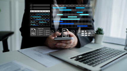 A business professional engages with a smartphone while managing project timelines and tasks in a modern office. The digital interface enhances productivity and organization. Gantry