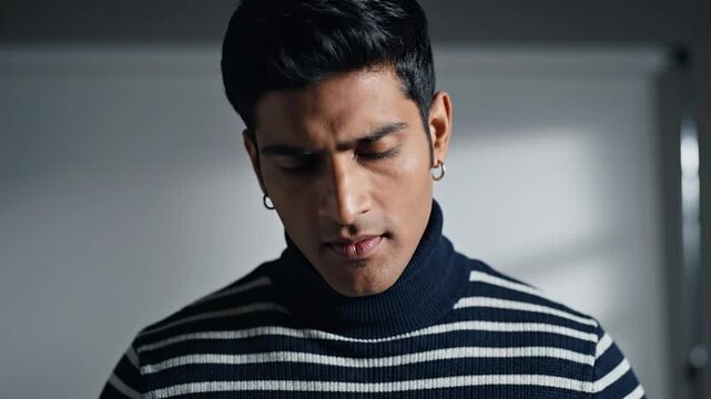 Close-up of a man with dark hair wearing a striped turtleneck sweater, smirking at the viewer