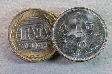 Kazakhstan Tenge and Polish Zloty Coins Comparison Close-Up. Close-up photograph of two national coins placed side by side: 100 Kazakhstani tenge and 1 Polish zloty. The image highlights differences 