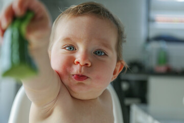 Baby eating cucumber. Copy space, background.