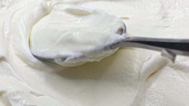 Scooping sour cream onto a spoon. Food ingredient, dairy product, eating concept