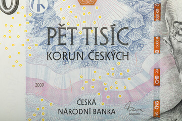 A detailed image showcases a section of a 5000 Czech Korun banknote, featuring the denomination inscription with abstract floral pattern. The banknote was issued in 2009.