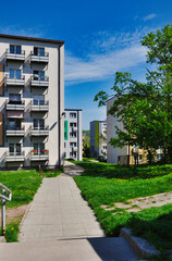 Osiedle bloków mieszkalnych z wielkiej płyty w stylu socrealistycznym z zielonym trawnikiem i chodnikiem w słoneczny dzień. © Pol Badger