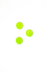 Three Round Green Pills With A Line In The Middle On A White Background
