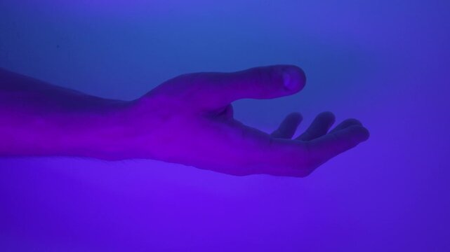 A male hand in a glowing neon liquid inside a laboratory