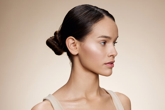 A profile shot of a young model with a neutral expression, showcasing flawless skin, natural makeup, and a clean background, perfect for beauty and skincare concepts