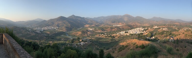 Naklejka premium Panoramic view of a mountain range with a small town in the valley below