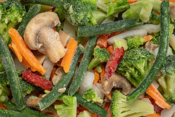 stir fry blend of frozen vegatables, broccoli, carrots, green beans, onions, red bell pepper and mushrooms - top view closeup background and texture