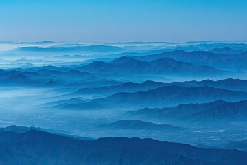 Panoramic view of layered blue mountain ranges with misty valleys under a clear sky
