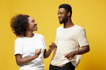 Obraz premium Happy young couple enjoying a joyful moment together against a vibrant yellow background in casual clothing, representing love and connection