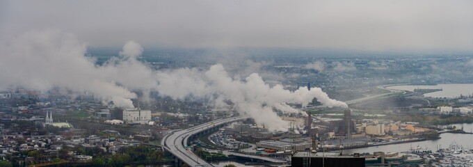 Industrial smokestacks emitting pollution over city and river