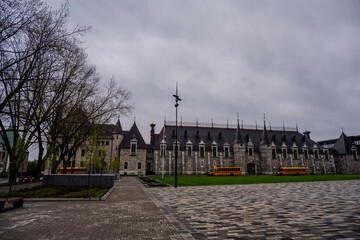 Historic stone building with turrets and school buses on cloudy day © Emad Aljumah