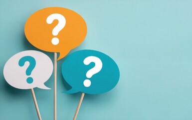 Three Colorful Paper Speech Bubbles with Question Marks on Wooden Sticks Over a Light Blue Background, FAQ Concept