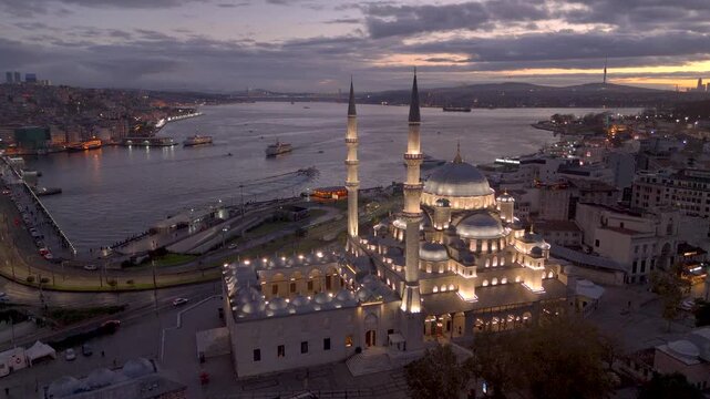 Aerial drone view of Istanbul historic Golden Horn, showing the Eminonu New Mosque or Yeni Cami, Galata Bridge, and Bosphorus at sunrise or sunset. Topkapi Palace and Hagia Sophia in the distance.