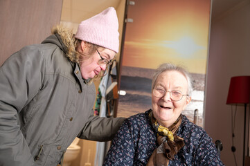Indoor portrait of 43-year-old woman with Down Syndrome visiting her 87-year-old mother