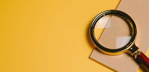 SEO concept. Magnifying glass with wooden handle on brown paper over yellow background, symbolizing focus and investigation concept