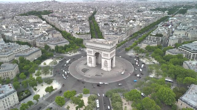 Aerial view of the famous landmark Triumphal Arch or Arc de Triomphe and Eiffel Tower surrounded by busy streets and lush greenery in the heart of the city Paris, France. Aerial drone orbiting flight