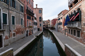 Canal in Venice with historic buildings and flags, Italy