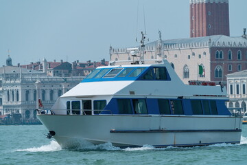White passenger ferry boat on Venice Lagoon with St Marks skyline, Italy