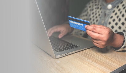online payment or shopping with laptop and blue credit card on wooden table for ecommerce or digital banking